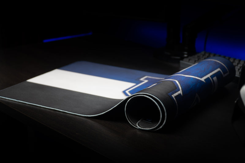 Kentucky Pride deskmat rolled from one end on a dark desktop, with its striped design visible.