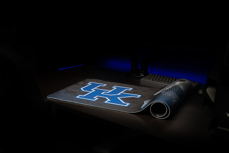 Kentucky Sound Wave deskmat partially rolled on a desktop with the blue UK logo visible.