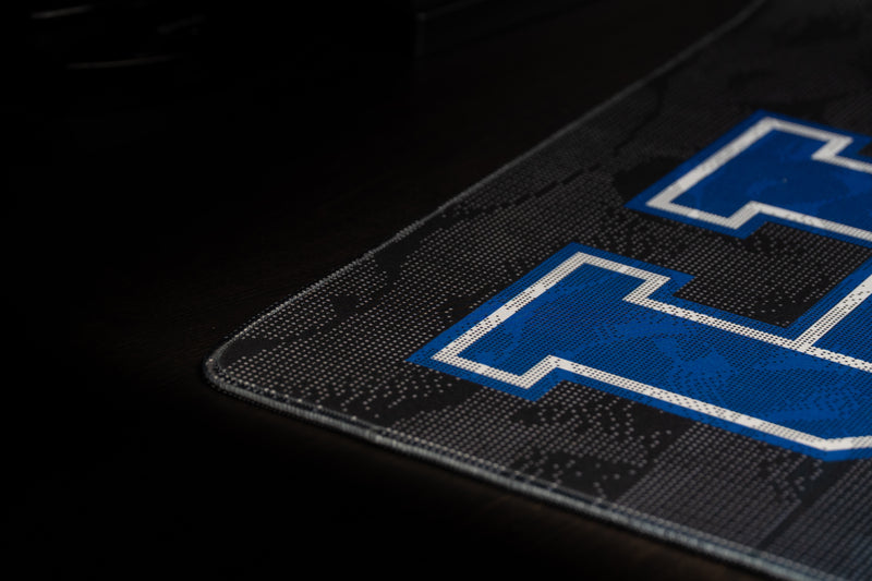 Close-up of the Kentucky Sound Wave deskmat's stitched edge beside the blue UK logo.