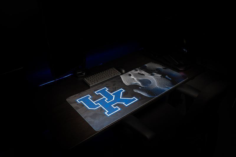 Wide view of the Kentucky Sound Wave deskmat in a dark gaming setup, showing the UK logo and wildcat design.
