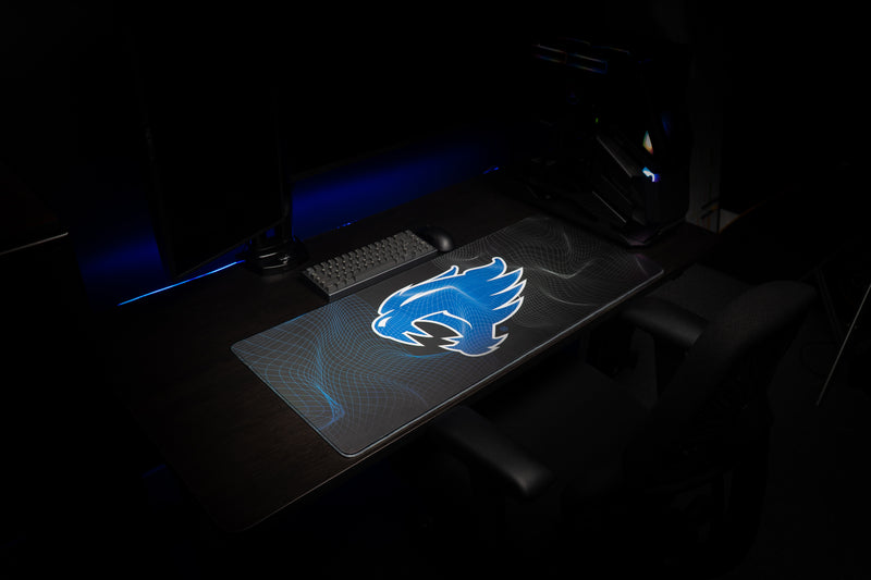 Kentucky Wildcat Afterglow deskmat at an angle in a dark gaming setup with blue wildcat graphic.