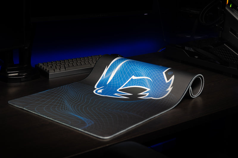 Kentucky Wildcat Afterglow deskmat partly rolled on a desktop, with its wireframe pattern visible.
