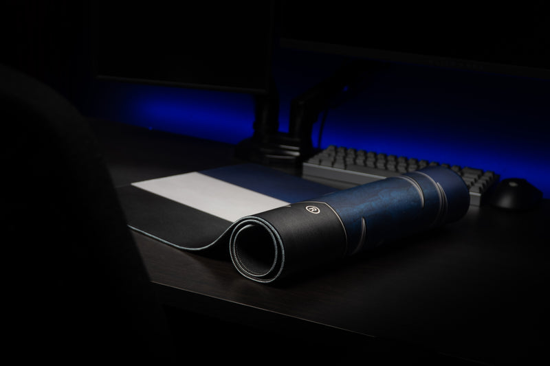 Kentucky Wildcat Pride deskmat partly rolled on a desk with its striped pattern visible.