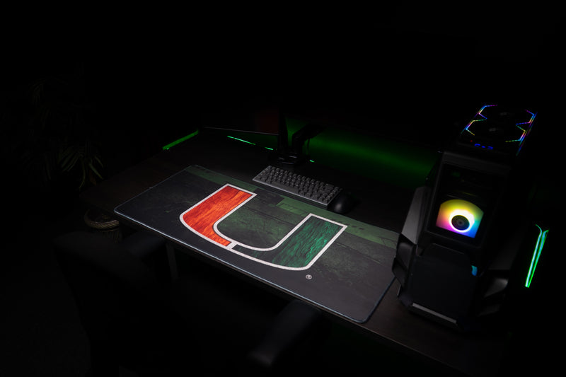 Full orange-and-green U artwork on the University of Miami Home Turf deskmat in a gaming setup
