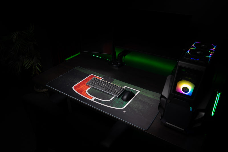 University of Miami Home Turf deskmat beneath a keyboard and mouse beside an RGB gaming PC