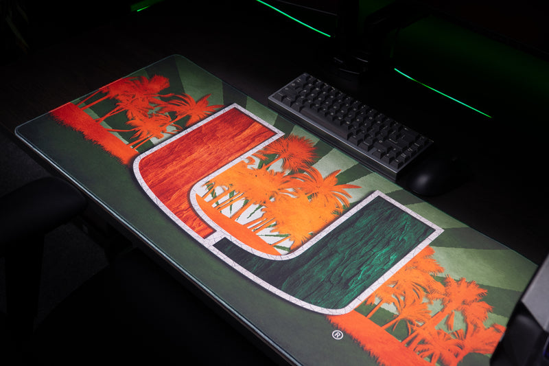 University of Miami Paradise deskmat angled view of the full U and palm tree artwork with a keyboard behind
