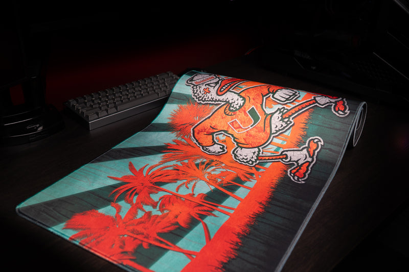 University of Miami Sebastian in Paradise deskmat partially rolled deskmat showing Sebastian and orange palms