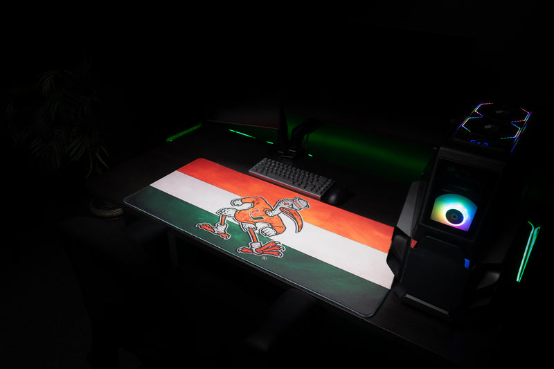 University of Miami Sebastian Pride deskmat angled view of the Sebastian Pride deskmat beside a gaming PC