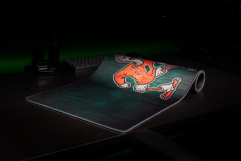 University of Miami Sebastian's Mark deskmat partially rolled deskmat showing Sebastian and wood-grain artwork