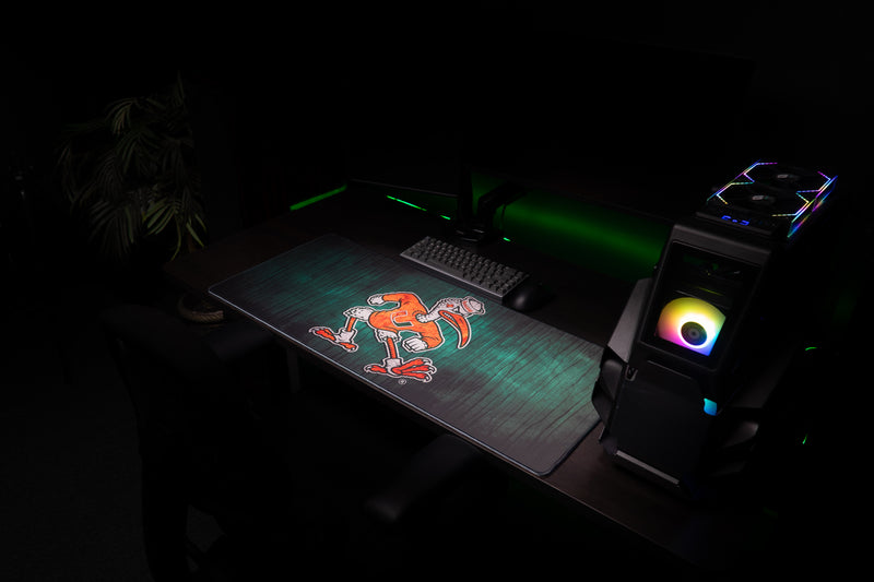 University of Miami Sebastian's Mark deskmat wide angled view of the Sebastian deskmat beside a gaming PC