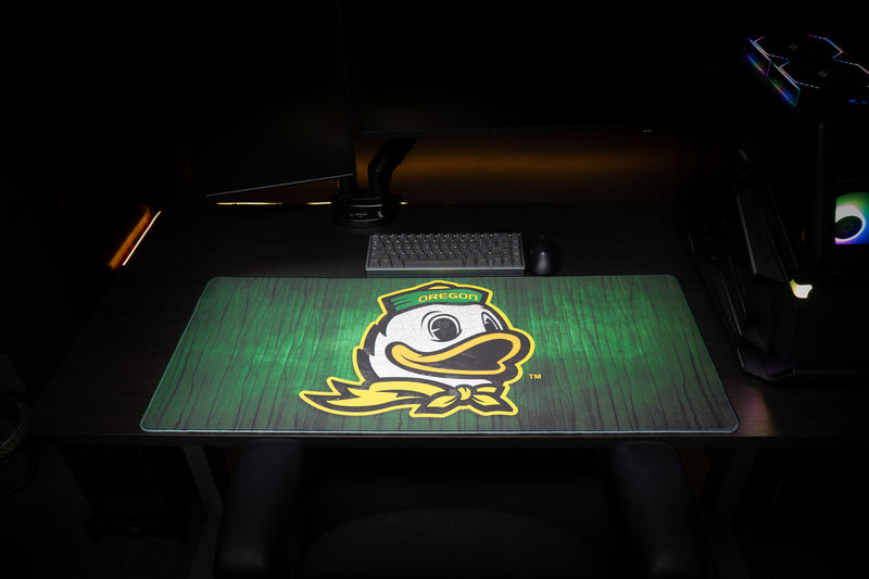 Front view of the Oregon Duck Country deskmat with duck mascot beneath a keyboard.