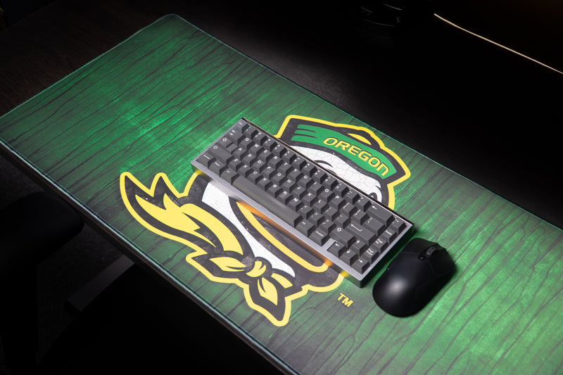 Keyboard and mouse resting on the Oregon Duck Country deskmat.