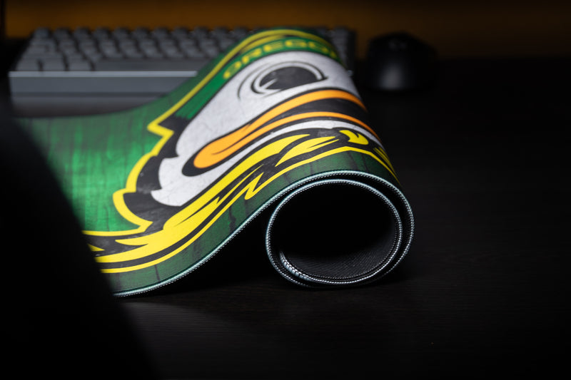 Rolled Oregon Duck Country deskmat showing the duck mascot and stitched edge.