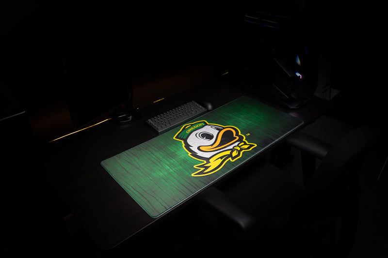 Wide view of the Oregon Duck Country deskmat in a dark gaming setup.