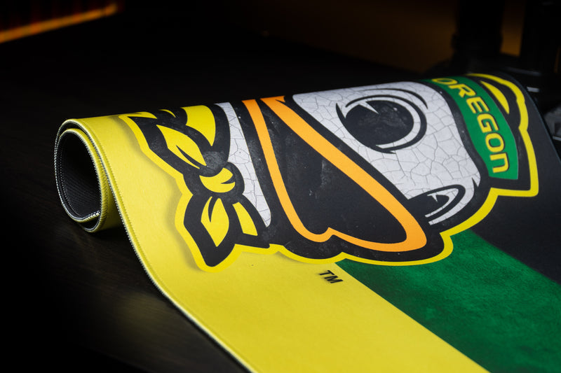 Close-up of the Oregon duck mascot on a partly rolled Duck's Pride deskmat.