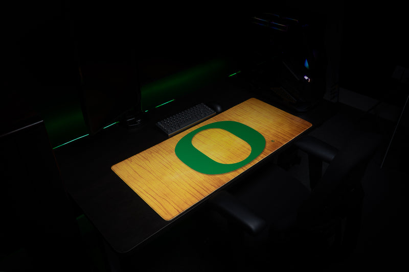 Angled view of the Oregon Emerald Grain deskmat across a gaming desk.