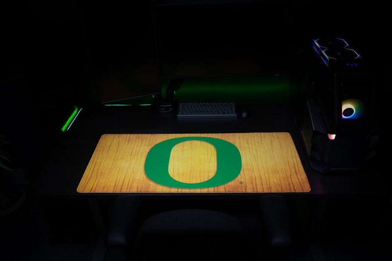 Front view of the Oregon Emerald Grain deskmat with green O on golden wood grain.