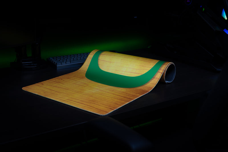 Oregon Emerald Grain deskmat partly rolled on a dark desktop.