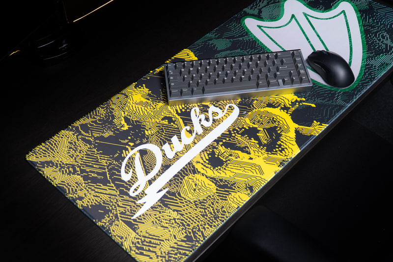 Keyboard and mouse on the Oregon Emerald Signature deskmat beside the webbed-foot emblem.