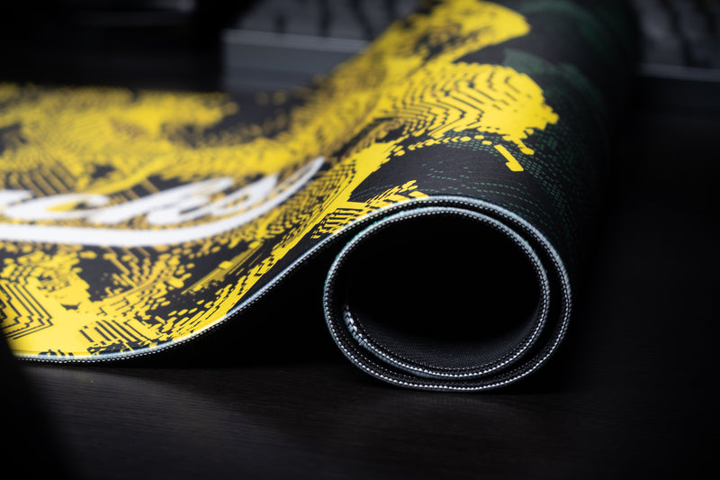 Rolled edge of the Oregon Emerald Signature deskmat showing its yellow pattern and stitched border.