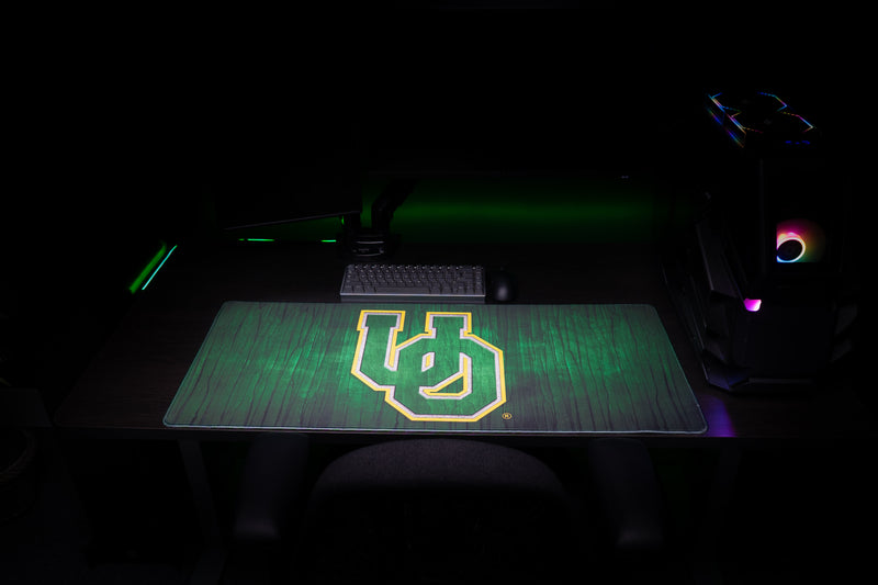 Front view of the Oregon Evergreen deskmat beneath a keyboard in a dark gaming setup.