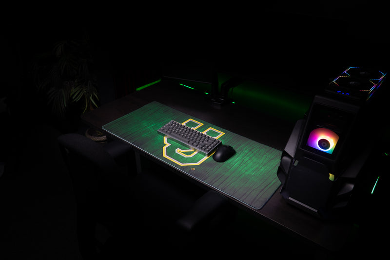 Keyboard and mouse on the Oregon Evergreen deskmat across a gaming workstation.