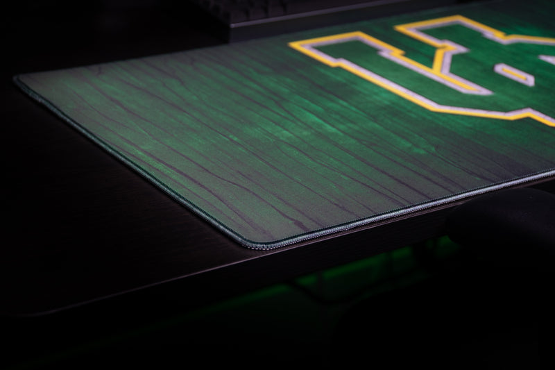 Close-up of the Oregon Evergreen deskmat's stitched corner and green wood-grain texture.
