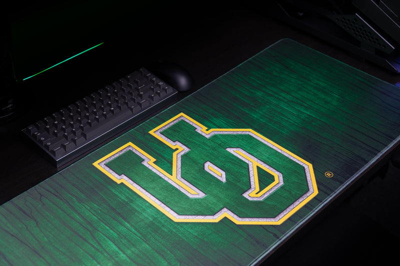 Close-up of the green-and-yellow UO logo on the Oregon Evergreen deskmat.