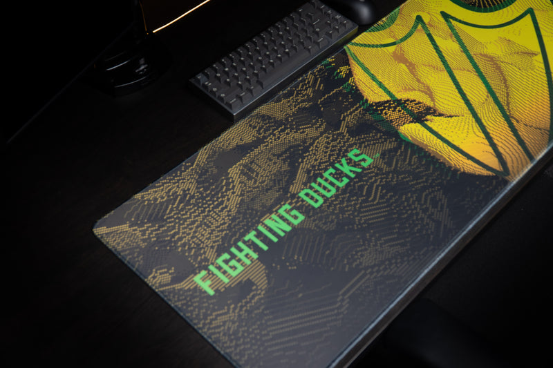 Angled view of the Oregon Fighting Ducks deskmat in a gaming setup.