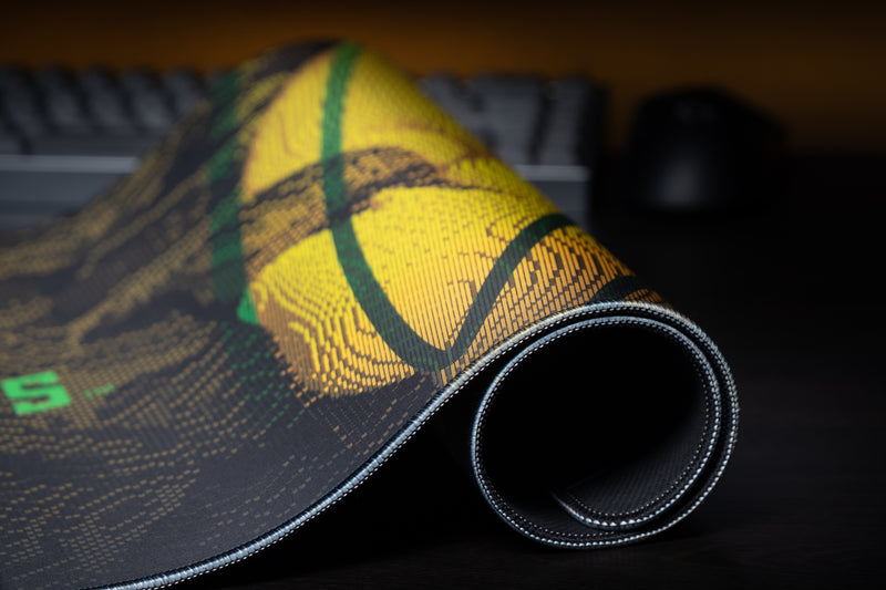 Rolled edge of the Oregon Fighting Ducks deskmat showing its yellow graphic and stitched border.