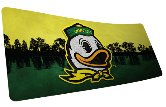 University of Oregon Home of the Ducks deskmat with duck mascot over a green lake and yellow sky.