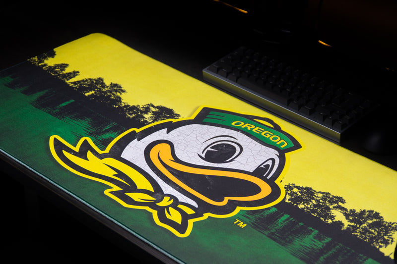 Close-up of the Oregon duck mascot and lakeside background on the Home of the Ducks deskmat.