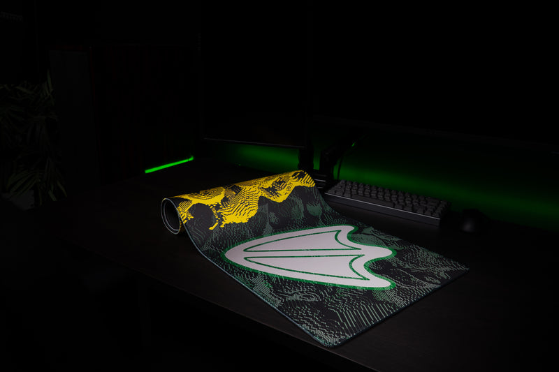 Oregon Flux deskmat partly rolled on a dark gaming desk.