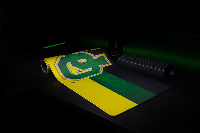 Oregon Pride deskmat partially rolled beside a keyboard in a dark gaming setup.
