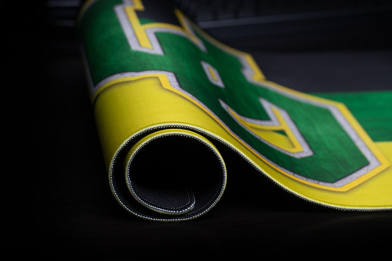 Close-up of the rolled Oregon Pride deskmat showing its stitched edge and UO logo.