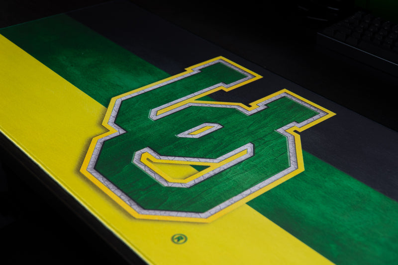 Close-up of the green-and-yellow UO logo on the Oregon Pride deskmat.