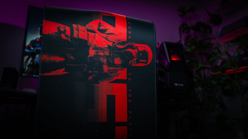 Side profile view of a red and black Rust hazmat deskmat displayed in a moody RGB gaming battlestation.