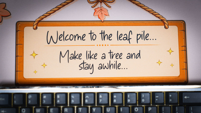 Close-up of the Welcome to the Leaf Pile deskmat featuring the cozy wooden sign reading "Welcome to the leaf pile... Make like a tree and stay awhile."