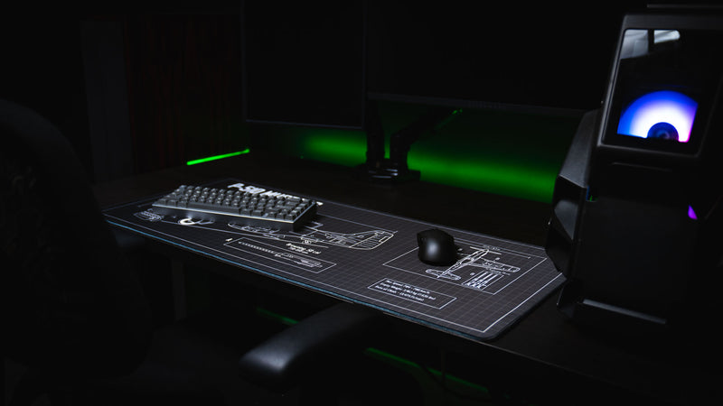 Angled view of the Wings of Liberty P-51D Mustang blueprint deskmat in a gaming setup, showcasing the detailed aircraft schematic, drafting grid, and stitched edges.