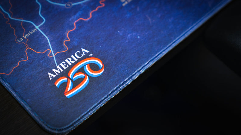 Close-up of the Zion Map deskmat highlighting the America 250 logo, premium stitched edge, and detailed blue topographic map artwork of Zion National Park.