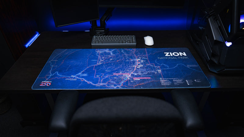 Zion Map deskmat featuring a detailed blue topographic map of Zion National Park displayed across a modern gaming desk with a mechanical keyboard and mouse.