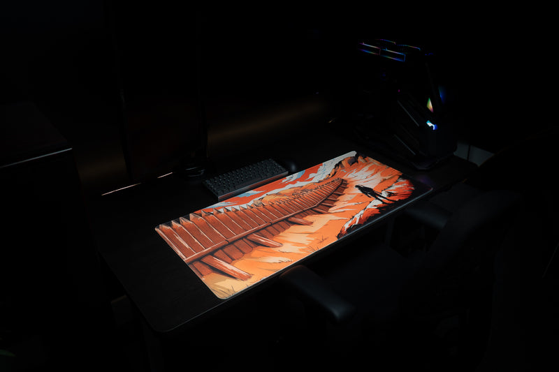 Angled view of Zodec's Great Wall of Chernarus XL desk mat on a desk in a dark room, with an RGB-lit gaming PC in the background