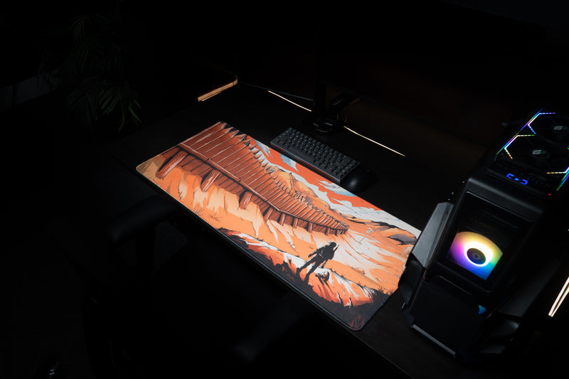 Zodec's Great Wall of Chernarus XL desk mat next to a gaming PC tower with rainbow RGB fans, with a keyboard and mouse on a dark desk