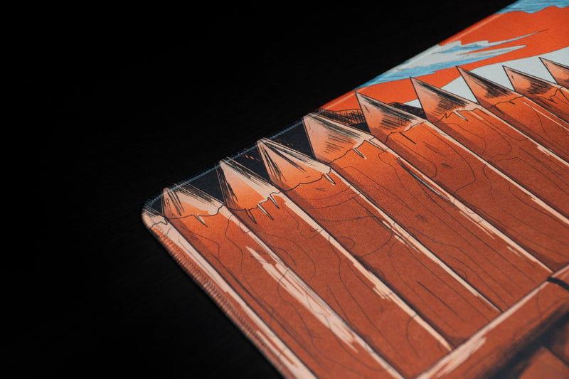 Detail of the rounded corner and stitched edge on Zodec's Great Wall of Chernarus desk mat, showing the printed wooden stake artwork