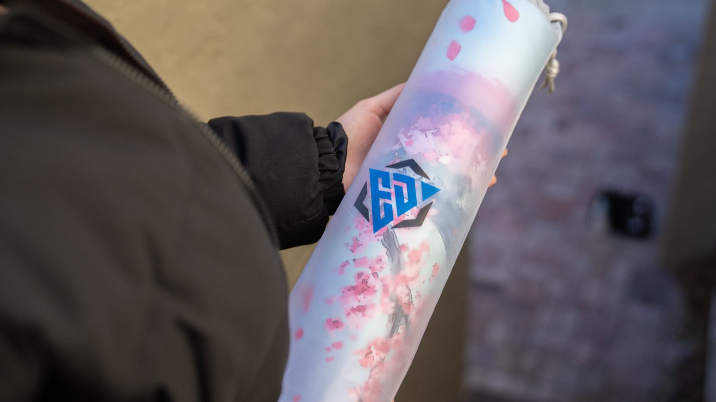A Cherry Blossom Serenity deskmat photographed on a bench beneath blossom